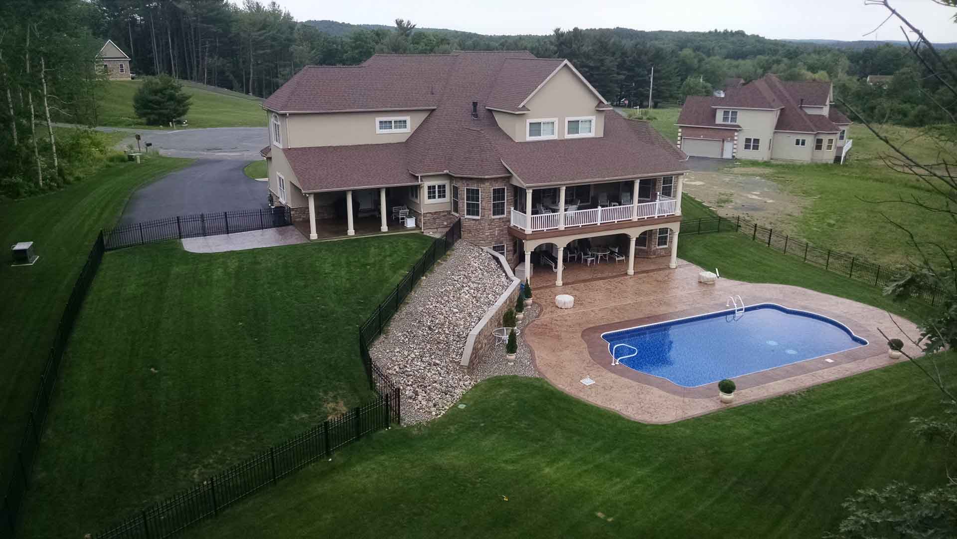 Aerial shot of large suburban home with an in-ground pool in the back